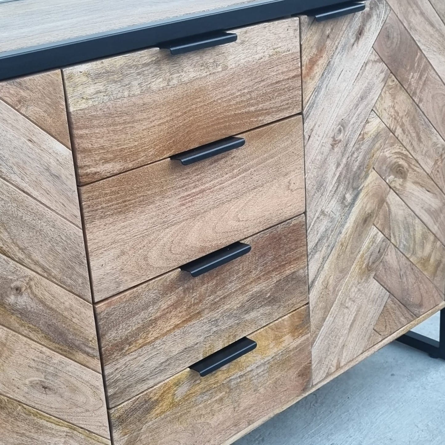 Ce buffet industriel moderne style herringbone Kukuu a été fabriqué à partir de bois massif de manguier et de métal. Il possède 4 tiroirs de rangement ainsi que 3 portes avec étagères et espaces de rangement. Mesures: 180 (L) x 46 (l) x 84 (H) cm. Kukuu, meubles industriels de qualité.