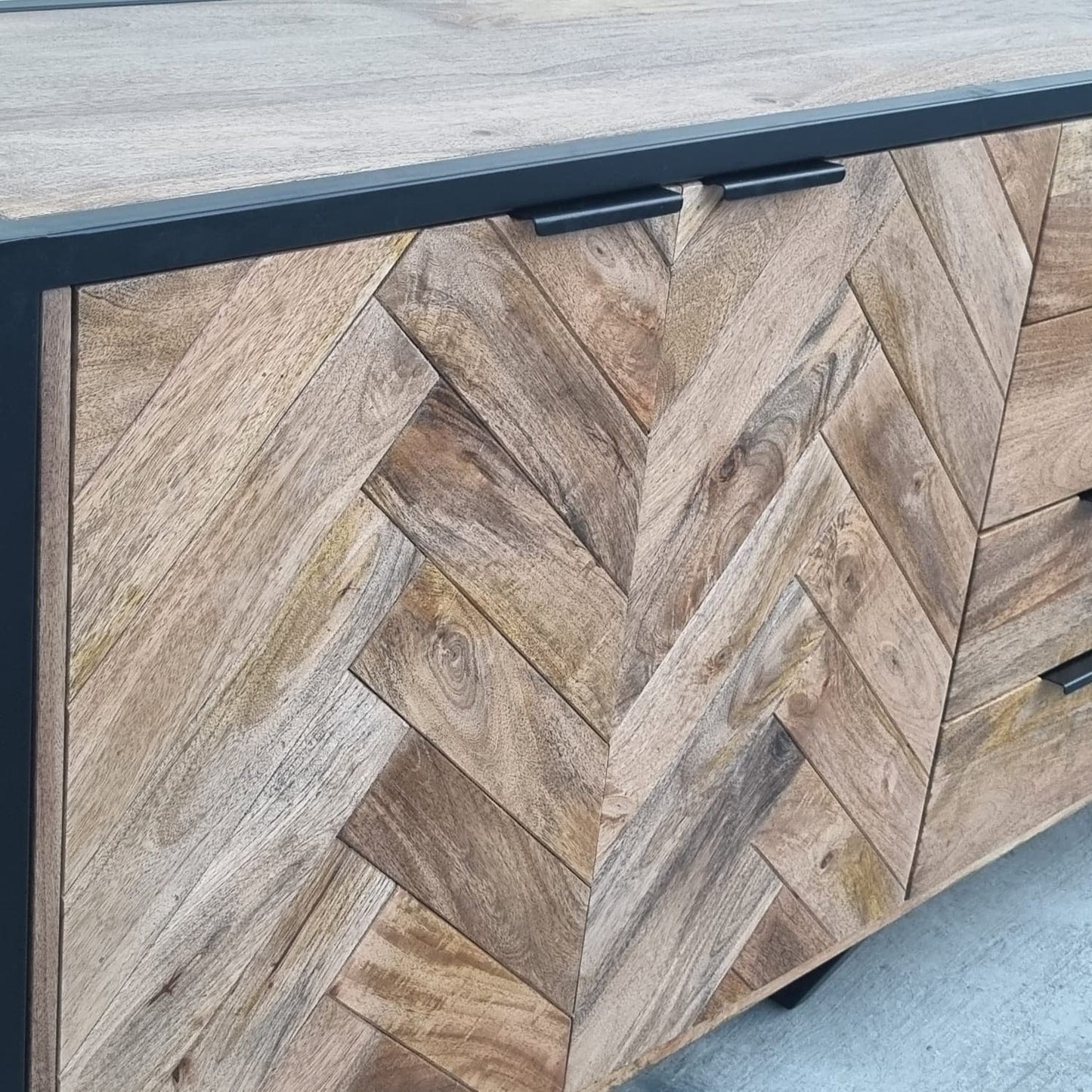 Ce buffet industriel moderne style herringbone Kukuu a été fabriqué à partir de bois massif de manguier et de métal. Il possède 4 tiroirs de rangement ainsi que 3 portes avec étagères et espaces de rangement. Mesures: 180 (L) x 46 (l) x 84 (H) cm. Kukuu, meubles industriels de qualité.