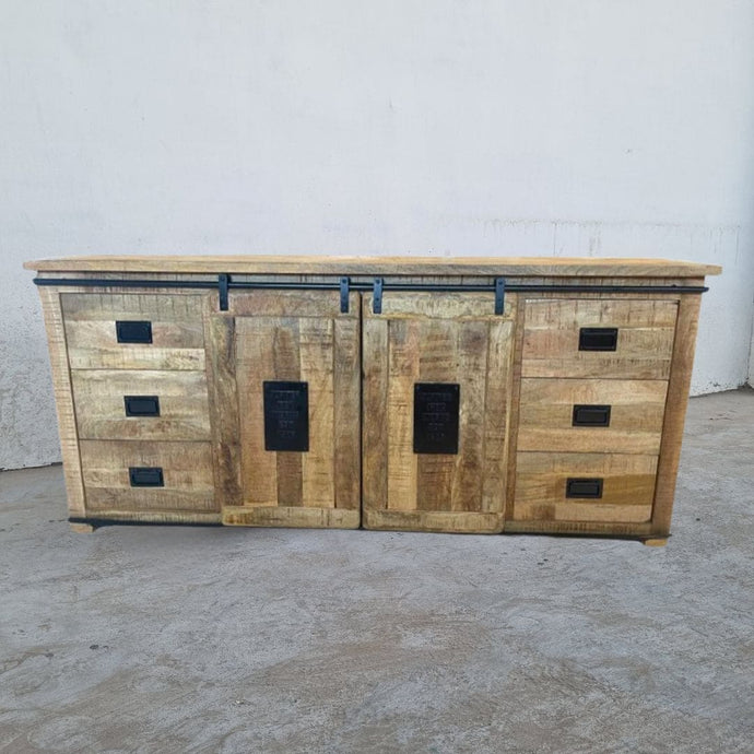 Ce bahut industriel fait de bois massif de manguier et métal, est composé de 6 tiroirs en bois, 2 portes coulissantes et d'une étagère centrale. Dimensions: 200 (L) X 45 (l) X 90 (H) cm. Kukuu, spécialiste en meubles industriels.
